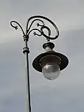 Latarnia uliczna z zawiniętą górą słupa. Oprawa skierowana jest w dół i wisi na zawiniętym słupie.