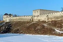 Zdjęcie, mury obronne i zamek w Szydłowie zimą.
