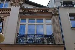 Dwunastokwaterowe okno po prawej stronie fasady kamienicy ze znajdującą się przed nim balustradą