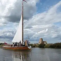 Wherry﻿(inne języki) – tradycyjna łódź wykorzystywana do żeglugi po The Broads, w tle ruiny opactwa św. Beneta﻿(inne języki)