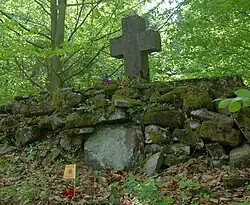 Kopiec z krzyżem na ścianie ogrodzenia