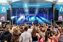 Uczestnicy Festiwalu Życia w Kokotku bawią się przed sceną w trakcie wieczornego koncertu Tribbsa, 8 lipca 2023 r.