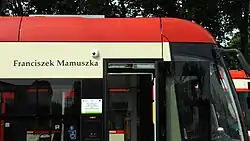 Zdjęcie fragmentu przedniej części tramwaju. Nad oknami pasażerów widnieje napis „Franciszek Mamuszka”.