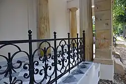 Detal grobowca Riedingerów w postaci kutego ogrodzenia i marmurowej posadzki. W tle filar ze śladami po kulach z czasów II wojny światowej.