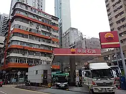 Zdjęcie wysokich budynków, między nimi znajduje się stacja benzynowa