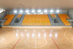 Parkiet hali sportowej z trybunami.