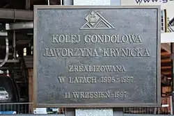 Metalowa tablica upamiętniająca budowę kolei, w budynku dolnej stacji