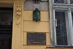 Zdjęcie. Fragment kamienicy. Pomiędzy oknem a drzwiami wejściowymi wmurowana tablica z informacją, że w tym domu mieszkał Jerzy Turowicz. Powyżej umieszczono numer kamienicy 7.