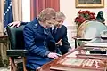 Prezydent Jimmy Carter i premier Wielkiej Brytanii Margaret Thatcher odczytują tekst z tabliczki przymocowanej do biurka, grudzień 1979.