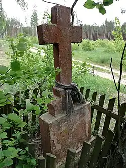 Stary krzyż wotywny z cyrylicznymi inskrypcjami na obrzeżach wsi