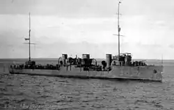 Zdjęcie czarno-białe przedstawia okręt z okresu, płynący na pełnym morzu, sfotografowany ukośnie z dziobem skierowanym w prawą stronę. Morze jest spokojne, z lekkimi falami, niebo bezchmurne. Na okręcie wywieszona jest bandera Estonii, choć rosyjskojęzyczny podpis na zdjęciu wymienia jego nazwę rosyjską, „Mikłucha-Makłaj”.