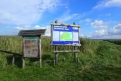 Zdjęcia tablic informacyjnych na tle łąk, szuwarów i nieba