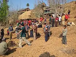 Zdjęcie przedstawia wioskę Kumpur. Na pierwszym planie widoczni są mieszkańcy osady, natomiast w tle widać zabudowę wioski