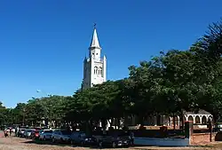 Wieża, widoczna zza pierzei drzew stojącej przy ulicy Teniente Rojas Silva