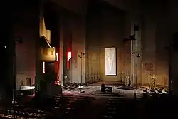 Słabo oświetlone wnętrze betonowego kościoła ze stołem ołtarzowym na środku