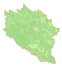 Mapa konturowa gminy Idrija, w centrum znajduje się owalna plamka nieco zaostrzona i wystająca na lewo w swoim dolnym rogu z opisem „Divje jezero”