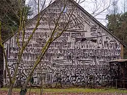 Jasna ściana budynku z powieszonymi setkami narzędzi