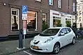 Samochód elektryczny ładowany na parkingu w Amsterdamie.