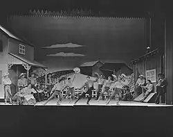 Zdjęcie przedstawiające ludzi z kapeluszami tańczącymi na scenie.