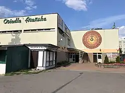 Neon z logiem osiedla oraz mozaika z układem planetarnym znajdujące się na budynku usługowym wchodzącym w skład osiedla Kępa Gocławska