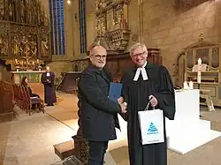 Podczas wizyty chóru ekumenicznego przy kościele Wang w partnerskim mieście Kamenz: ksiądz Pech przekazuje pozdrowienia burmistrza Karpacza.