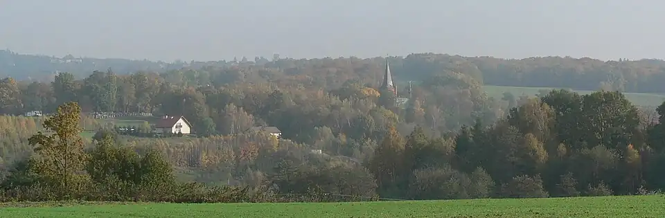 Poręba Radlna k.&nbsp;Tarnowa. Po lewej cmentarz z kaplicą cmentarną, po prawej kościół. Panorama przysiółka Sutkówka. 2009
