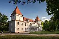 Pałac o szarej elewacji z czerwonym dachem. Wejście do budynku z portykiem o 4 filarach, zwieńczony tarasem. Po obu stronach wejścia dwa rzędy okien i widoczne fragmenty wieżyczek