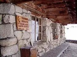 Tabliczka przy wejściu do schroniska z oznaczeniem wysokości nad poziomem morza