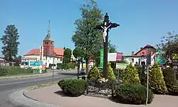 Krzyż przydrożny, w tle kościół św. Jana Chrzciciela