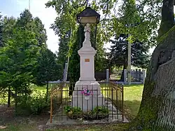 Zadaszona kapliczka przydrożna, w której wnętrzu znajduje się rzeźba przedstawiająca świętego Onufrego w pozycji klęczącej z różańcem w rękach