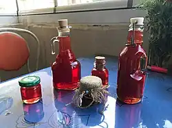 Zdjęcie, kilka pojemników z czerwonym olejem z dziurawca, stoją na niebieskim blacie