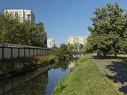 Kanał łączący stawy, widok od wchodu. Po lewej, za ogrodzeniem, widoczny pawilon dyrekcji osiedla, gdzie w przeszłości miały znajdować się urządzenia zagłuszające