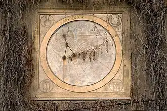 Zegar słoneczny przed renowacją znajdujący się na frontowej ścianie budynku. Na tarczy wypisane motto rodu Tarnowskich "Tendite ad astra viri"