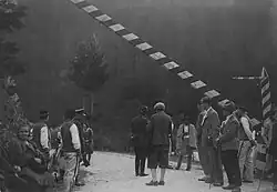 Miejsce przejściowe po drogach ulicznych, grupa osób, m.in. górale i funkcjonariusze Straży Granicznej, przy szlabanie granicznym. Z lewej widoczny rower(1930–1933)