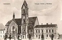 Kościół ewangelicki w Tarnowskich Górach, a po jego prawej stronie budynek plebanii (pocztówka z lat 1914–1919)