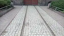 Zdjęcie. Tor tramwajowy w bruku przed bramą poczty przy alei Niepodległości.