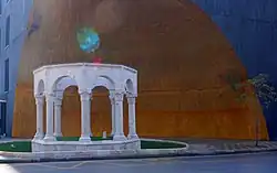 Ośmioboczny biały kamienny grobowiec, z tyłu łukowata złota ściana budynku