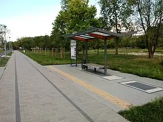 Widoczny zaznaczony ślad nieistniejących torów ŚKP i współczesna rekonstrukcja dawnego przystanku kolejowego