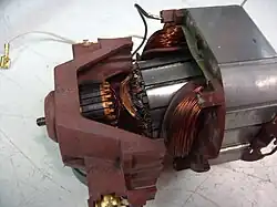 Wewnątrz wirnik z widocznym komutatorem. Wokół komutatora obudowa ze szczotkotrzymaczami. Wokół biegunów wirnika stojan z dwoma uzwojeniami.