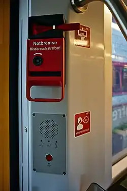 Zdjęcie pociągu przy drzwiach zawiera: wyżej: Urządzenie alarmowe PAD, niżej: interkom CFA.