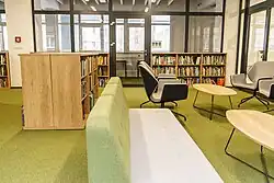 Na zdjęciu widać regały z książkami, fotele i stoliki.