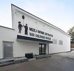 Budynek wytynkowany na biało. Pośrodku wejście, a nad nim napis w języku bośniackim i angielskim z nazwą muzeum. Po lewej stronie napisy sylwetki dwójki dzieci, które trzymają w ręku balonik.