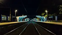 Widok na przystanek z poziomu torów w kierunku wschodnim nocą.