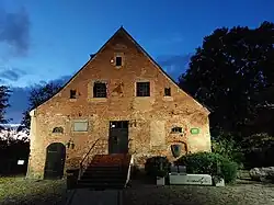 Zdjęcie ceglanego frontu budynku. Rzucają się w oczy zamurowane okna i drzwiami w różnych stylach architektonicznych.