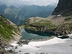Zmarzły Staw w lipcu z częściową pokrywą lodową, w tle Jaworowe Wierchy